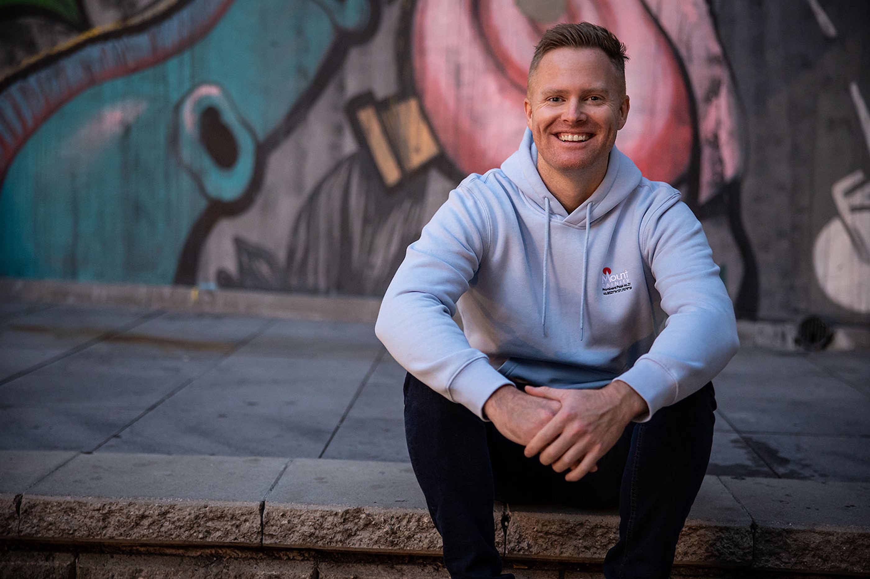 Tim Brown sitting on steps in front of a painted mural
